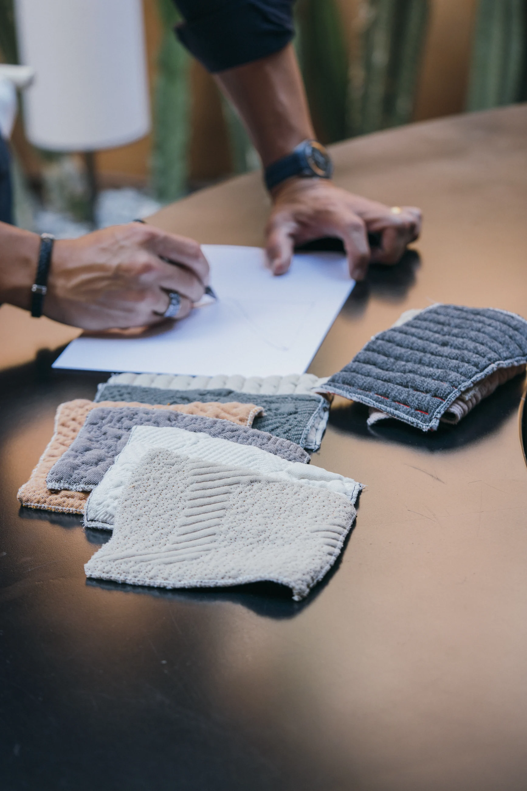 André Gurgel sketching beside a selection of textured fabric samples