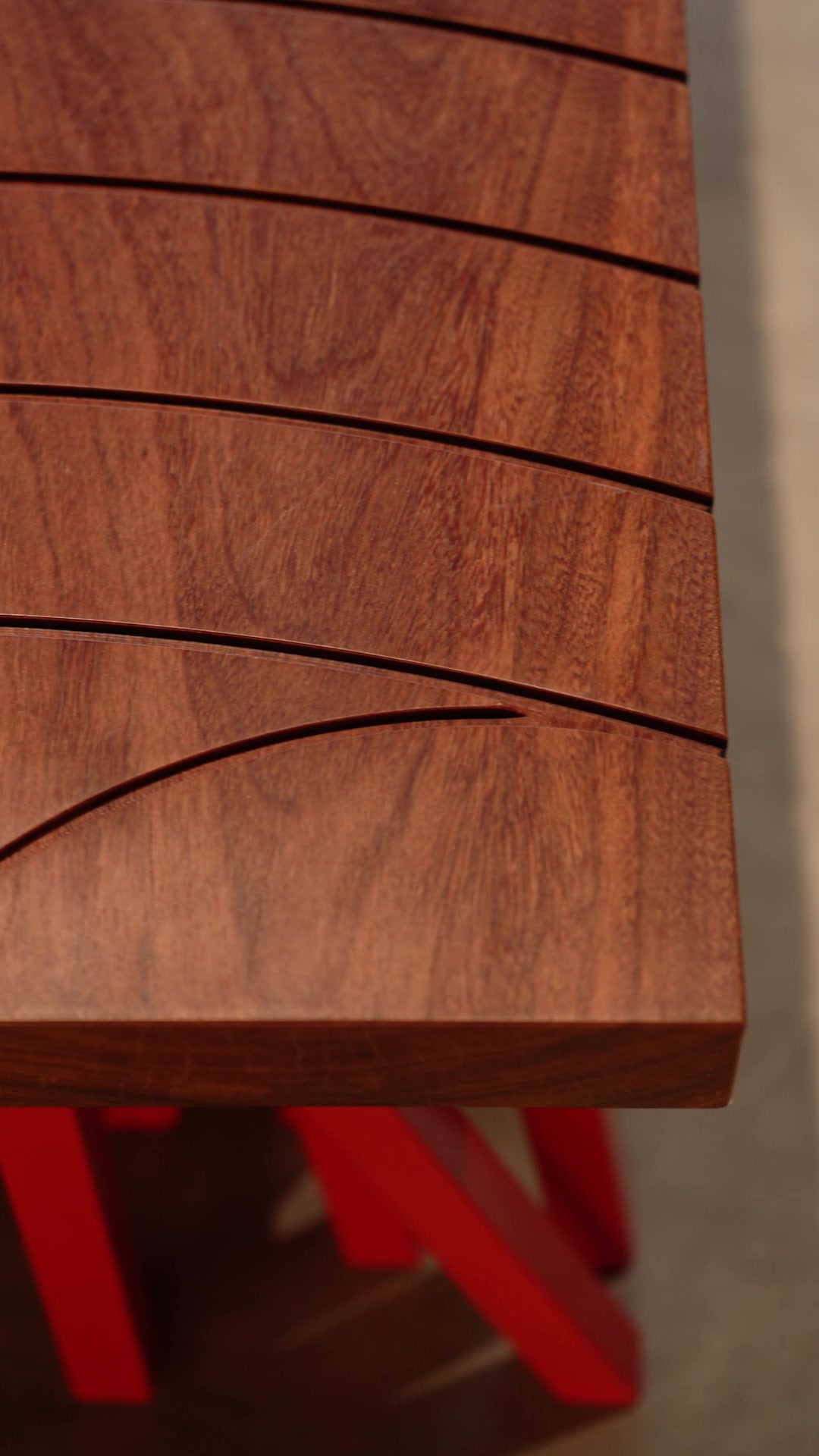 Close detail of the Banco Centopeia wooden surface and red supports
